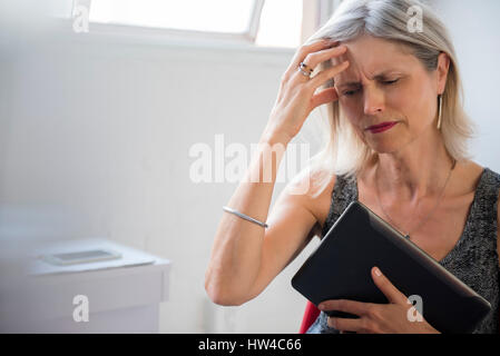 Frustriert kaukasischen Frau mit digital-Tablette Kopfschmerzen leiden Stockfoto