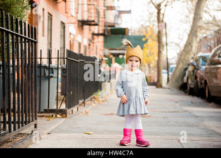 Lächelnd kaukasischen Baby Mädchen tragen Krone Hut auf Stadt Bürgersteig Stockfoto