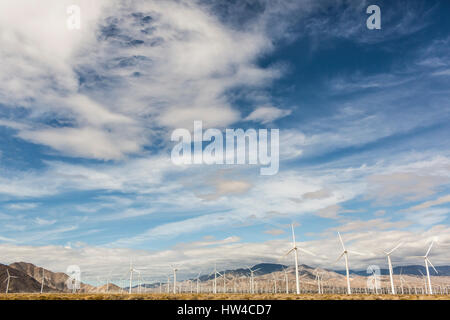 Windkraftanlagen unter bewölktem Himmel in abgelegenen Landschaft Stockfoto