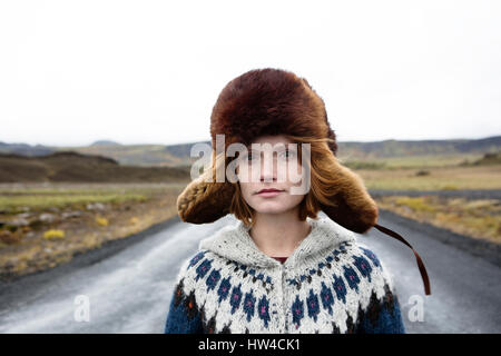 Kaukasische Frau trägt Pullover und Pelzmütze in der Mitte der Straße Stockfoto