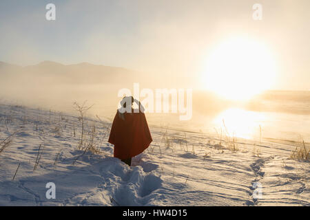 Kaukasische Frau Abschirmung Augen in Winterlandschaft bei Sonnenuntergang Stockfoto