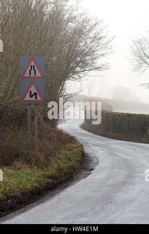 Straße verengt und Doppel beugt sich zuerst auf der linken Seite, auf einer Straße in Wales mit leichten Winternebel. In der Nähe der Siedlung Glanusk in Brecon Nationalpark Stockfoto