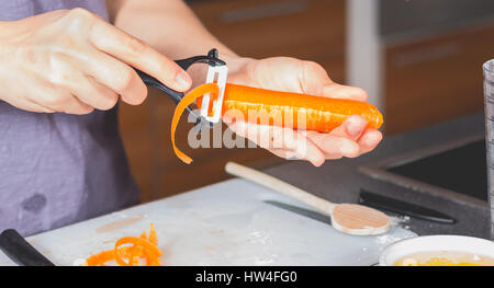 Kochen, Schälen von Karotten mit Keramik Messer auf einer Arbeitsplatte Stockfoto