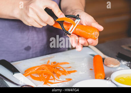 Kochen, Schälen von Karotten mit Keramik Messer auf einer Arbeitsplatte Stockfoto