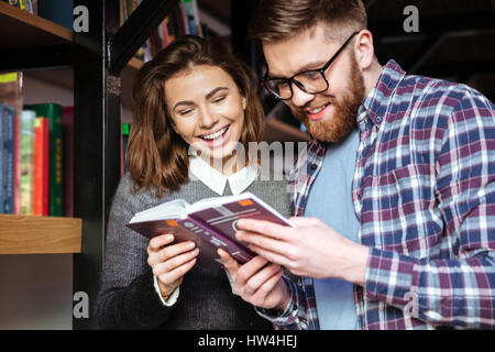 Zwei glückliche Schüler gemeinsam in der Bibliothek mit Büchern Stockfoto