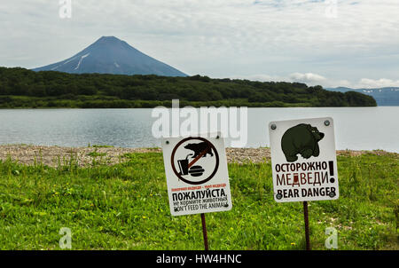 Schilder warnen vor der Gefahr begegnen Touristen mit Bären auf Hintergrund der Kurilen See und Iljinski Vulkan. Stockfoto