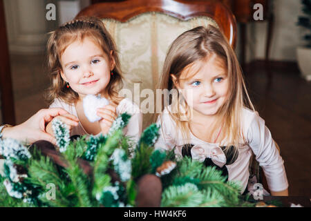 zwei kleine Mädchen machen einen Weihnachtskranz Stockfoto