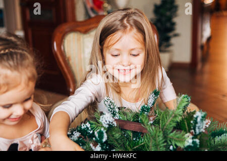 zwei kleine Mädchen machen einen Weihnachtskranz Stockfoto