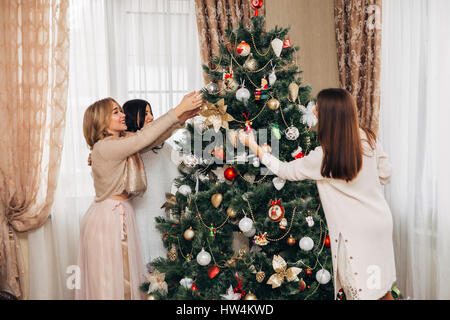 drei Schwestern schmücken den Weihnachtsbaum Stockfoto