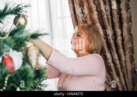 schöne Frau schmückt den Weihnachtsbaum Stockfoto