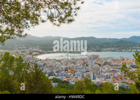 Blick durch die Bäume, vom Hang des nahe gelegenen Stadt natürlich umrahmen: San Antonio Sant Antoni de Portmany in Ibiza.  Marina mit ankern Boote. Stockfoto