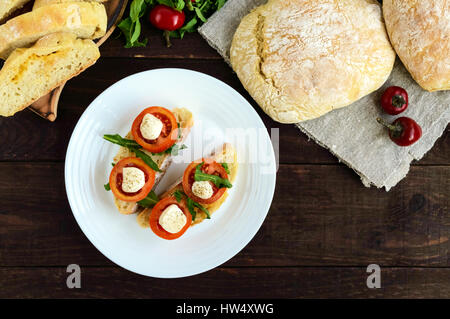 Bruschetta mit Rucola, Tomaten, Mozzarella, Olivenöl auf Chiabatta Scheiben. Leichtes Frühstück. Die Ansicht von oben Stockfoto