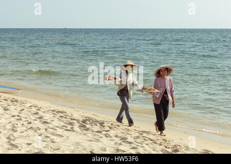 Phu Quoc, Vietnam - 7. April 2014: Zwei lächelnde einheimische Frauen am Strand entlang spazieren und Verkauf von Süßigkeiten für Touristen am 7. April 2014, Phu Quoc Island, Stockfoto