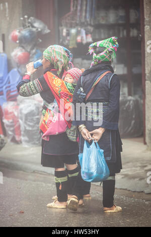 Sapa, Vietnam - 6. Mai 2014: Hmong Frauen in traditioneller Kleidung mit modernen Soda auf dem lokalen Markt in Sapa Dorf Lao Cai, Nordvietnam Stockfoto