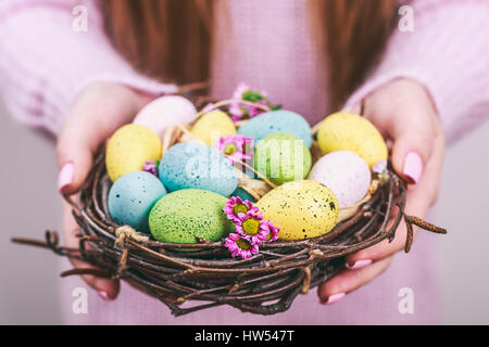 Frau Hände halten bemalte Ostereier in einem kleinen Nest. Durchtrainierten Bild. Selektiven Fokus. Stockfoto