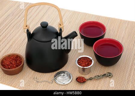 Saflor Kräutertee mit orientalische Teekanne und Tassen mit Sieb und alte Löffel auf Bambus auf weißem Hintergrund. Auch verwendet in der chinesischen Kräutermedizin. Stockfoto