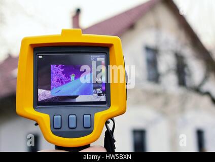 Aufnahme Wärmeverlust des Daches auf Kosten des Hauses mit Infrarot-Wärmebildkamera in der Hand. Stockfoto