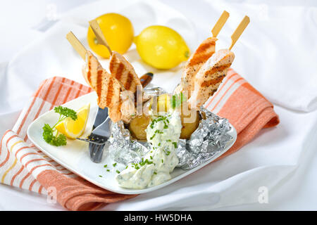 Leckere Ofenkartoffeln mit Sauerrahm und gegrilltem Lachs Spieße Stockfoto