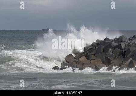 Weißer Schaum aus einer Brandung über Wellenbrecher Blöcke in San Sebastián (Baskenland, Spanien) 2017. Stockfoto