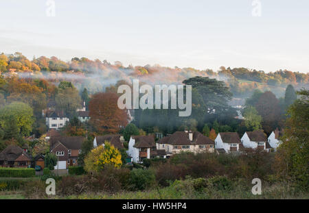 Suburban Wohnsiedlung am Woodmansterne, Banstead in der Nähe von Croydon in Surrey, England. Mit Herbst (Herbst) Farben in den Bäumen und Nebel oder Rauch Stockfoto