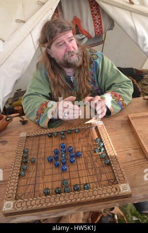 Mann an der Schlacht von Hastings Re-enactment Veranstaltung auf dem Gelände der Battle Abbey, das Spielen des Spieles hnefatafl. Angelsächsische Lager. Stockfoto