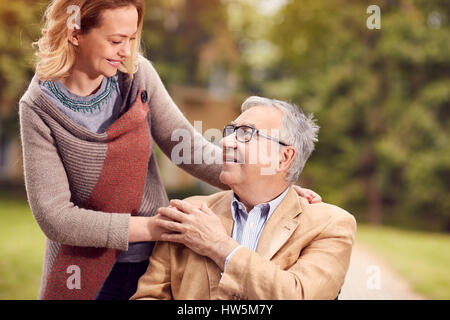 Tochter genießen mit ihrem senior lächelnden Vater im Rollstuhl Stockfoto