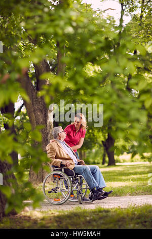 glückliche Zeit mit der Familie-Smiling älterer Mann im Rollstuhl im Gespräch mit Tochter im park Stockfoto