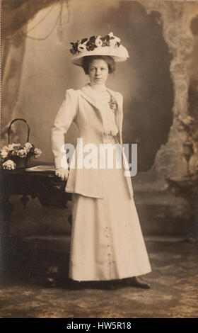 Vintage Studioportrait, Dame, die einen großen Hut mit Blumen auf Stockfoto