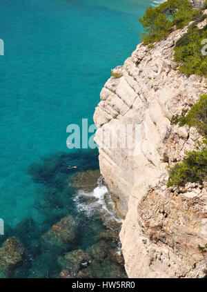 Menschen schwimmen im transparenten türkisen Wasser des balearischen Meer in der Nähe von Cala Mitjana auf Menorca Balearen-Insel in Spanien Stockfoto