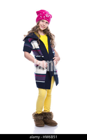 Niedliche kleine lächelnde Mädchen mit lockige Frisur tragen bunte Pullover, Hemd, Hose und Hut isoliert auf weißem Hintergrund. Winterkleidung Stockfoto