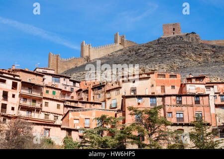 Häuser und Straßen von Albarracin gegen den Hang des Hügels mit der Stadtmauer auf der Oberseite an einem sonnigen Tag unter einem blauen Himmel. Albarracin, Teruel, Spanien. Stockfoto