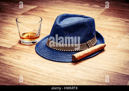 blaue Mütze mit Zigarre und teuer trinken Whisky oder Rum auf Holzboden. Gentleman oder Hipster entspannen Konzept Stockfoto