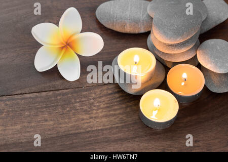 Spa-Komposition mit Kerzen Kies, Steinen und Blumen auf Holztisch Stockfoto