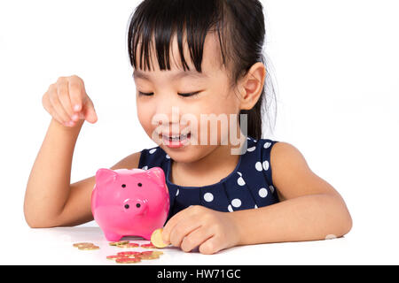 Asiatische kleine chinesische Mädchen setzen Münzen ins Sparschwein isoliert auf weißem Hintergrund Stockfoto