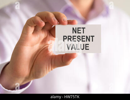 Closeup on businessman holding a card with NPV NET PRESENT VALUE message, business concept image with soft focus background Stockfoto