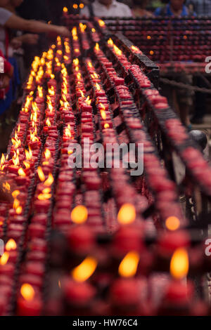 Lange Reihen von vielen kleinen roten Kerzen von Gläubigen auf eine religiöse Stätte, Mittelpunkt mit Schärfentiefe. Stockfoto
