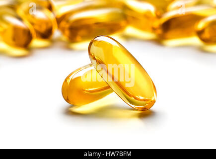 Zwei Kapseln Omega 3 isoliert auf weißem Hintergrund und viele andere Kapseln auf unscharfen Hintergrund. Großaufnahme, hochauflösende Produkt. Health care con Stockfoto