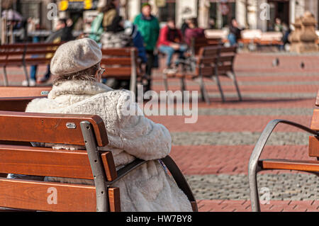 Ältere Frau ruht auf einer Bank in einem Platz. Echte Menschen. Stockfoto