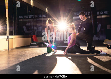 Junge sportliche Frau stretching Pilates-Übungen mit Übung Trainer Stockfoto