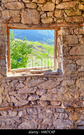 Schauen Sie durch Fenster aus verlassenen Haus in den Bergen Stockfoto