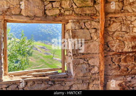 Schauen Sie durch Fenster aus verlassenen Haus in den Bergen Stockfoto