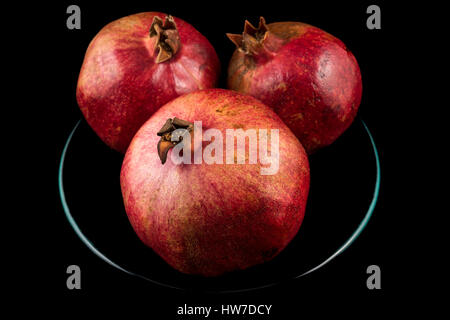 Drei Granatäpfel auf Platte mit schwarzem Hintergrund Stockfoto