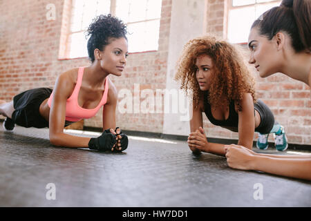 Gruppe von weiblichen Liegestütze zusammen im Fitness-Studio zu tun. Drei junge Frauen im Fitnessraum trainieren. Stockfoto