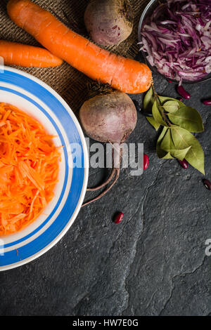 Rüben, Karotten und Kohl während des Kochens. Zusammensetzung auf einem dunklen Hintergrund. Platz für Text. Stockfoto