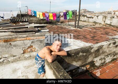 Kuba, Provinz Ciudad de la Habana, Havanna, Centro Habana Bezirk, Portrait eines jungen kubanischen und Kleidung trocknen auf der Terrasse eines Mehrfamilienhauses und Blick über die Dächer der Innenstadt von Habana Stockfoto