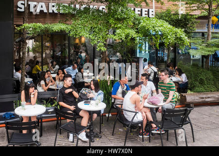 Junge Leute sitzen draußen Kaffee von Starbucks, Ho-Chi-Minh-Stadt, Vietnam Stockfoto