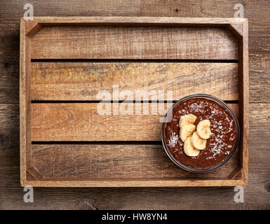 Schokolade Chia Pudding mit Banane in eine Glasschüssel auf grauem Beton Hintergrund Stockfoto