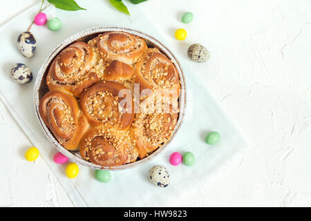 Ostern Gebäck. Frische hausgemachte cremige Zimtschnecken mit Nüssen. Zimtschnecken mit Frischkäse für Osterfrühstück mit Osterdekoration hautnah. Stockfoto