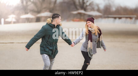 Schöne junge Paar läuft an einem Strand auf Winterzeit Stockfoto
