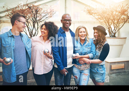 Junge Männer und Frauen Freunde in Freizeitkleidung stehen in der Nähe im Petanque Spiel Club mit silbernen Kugeln, lächelnd posiert für die Kamera Stockfoto